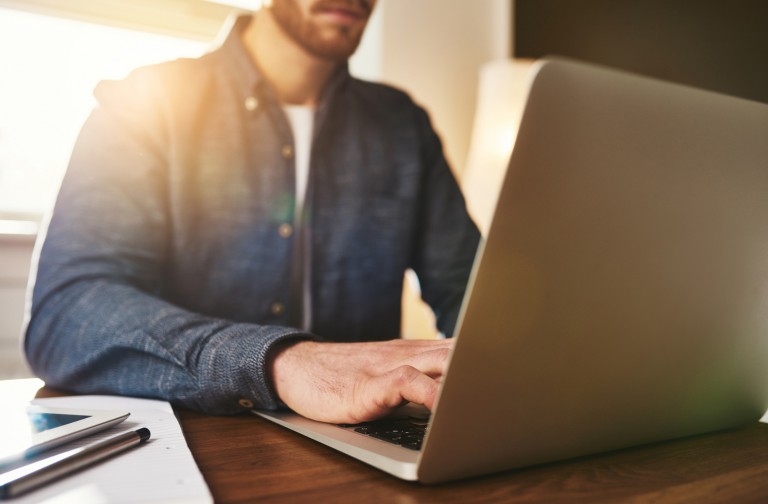Homem concentrado pesquisando no computador como sair do vermelho