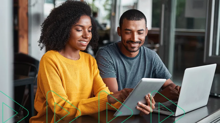 Empreendedores sorrindo enquanto usam seu sistema de gestão online no computador