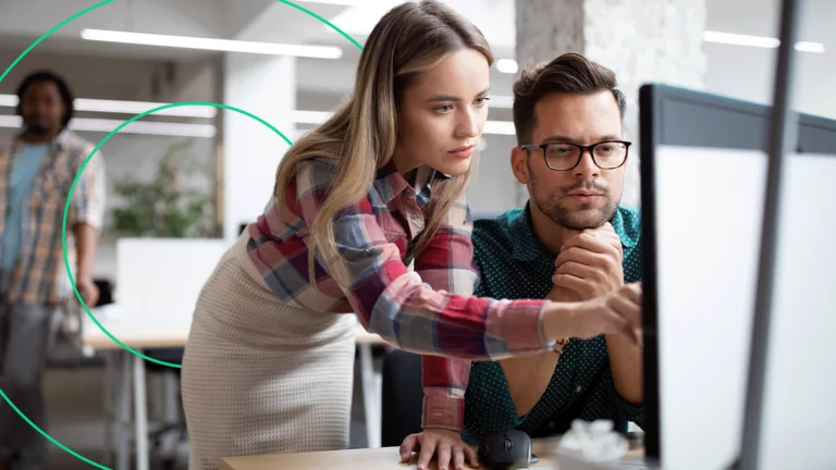 Duas pessoas no escritório da empresa, analisando informações no computador e discutindo sobre o melhor plano de marketing