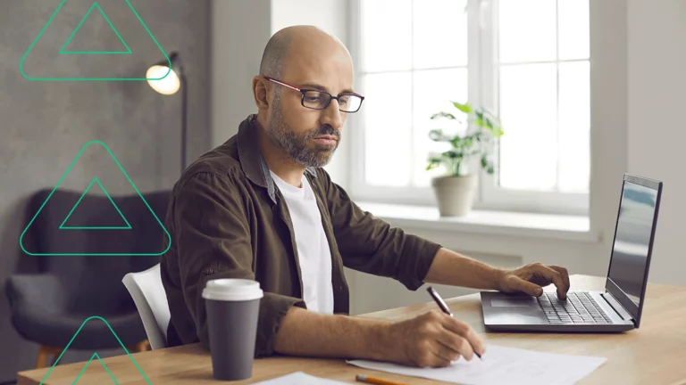 Empresário preenchendo uma nota de devolução no computador enquanto olha a nota original