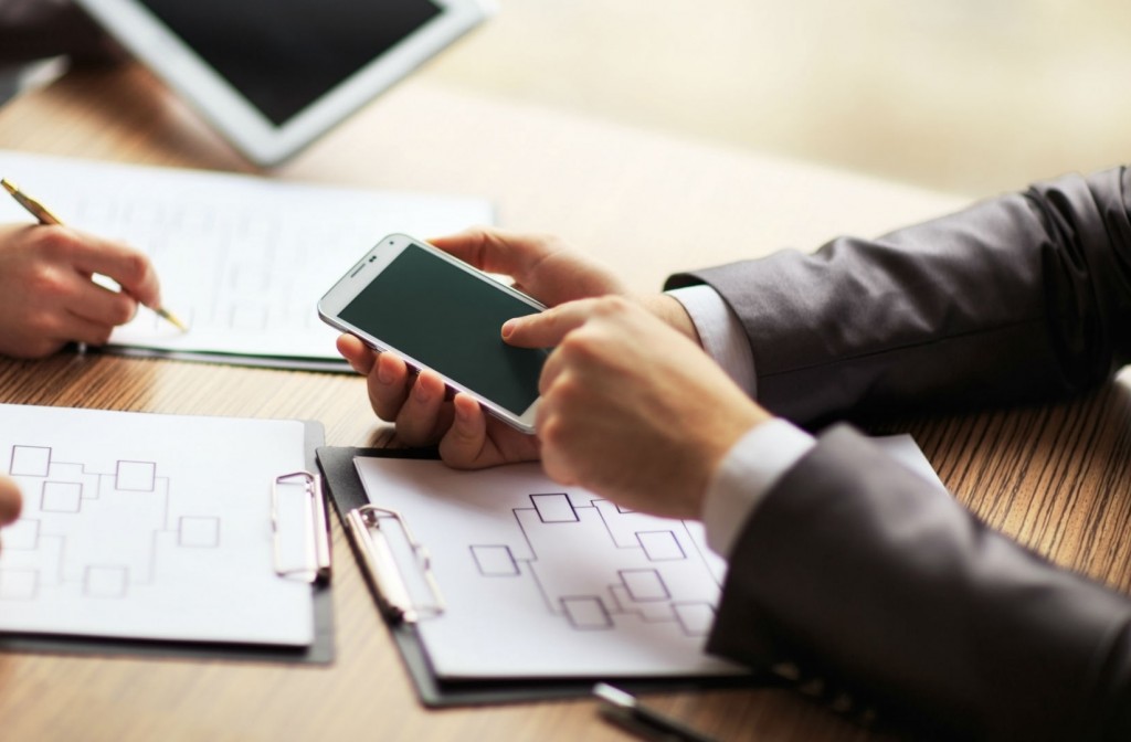 Empreendedor explicando para outras pessoas como funciona o WhatsApp Business, apontando para o mesmo na tela do seu celular