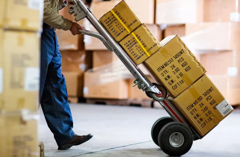 Pessoa utilizando carro de carga para mover produtos em caixas