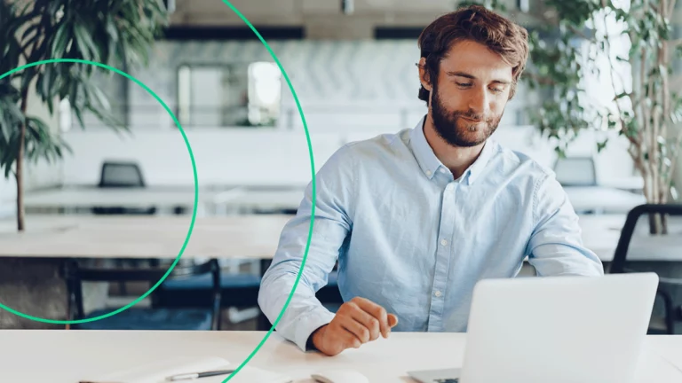 Em seu local de trabalho, empreendedor está contente enquanto assiste webinar de SEO em seu notebook