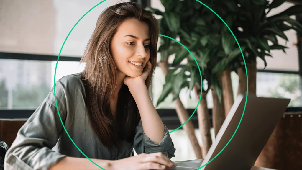 Empreendedora sorrindo enquanto assiste o webinar da Bling com a Total Express em seu notebook