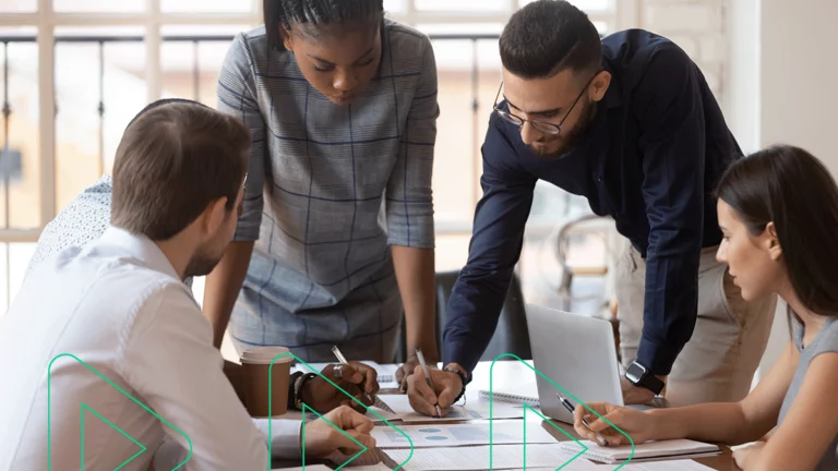 Grupo de pessoas discutindo sobre vários relatórios de indicadores do varejo espalhados pela mesa