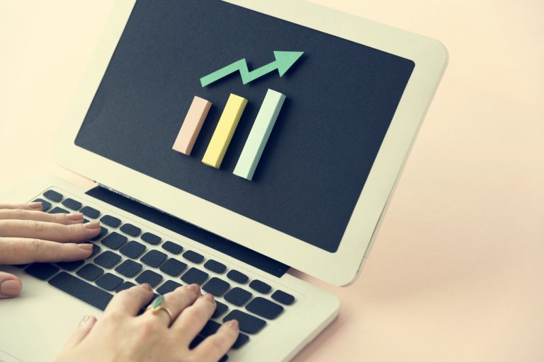 Pessoa digitando em um notebook, que mostra um gráfico de barras na tela, do resultado das campanhas com Google Ads