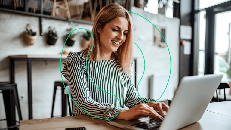 Mulher de negócios sorrindo enquanto usa um notebook para conferir dicas de como vender mais
