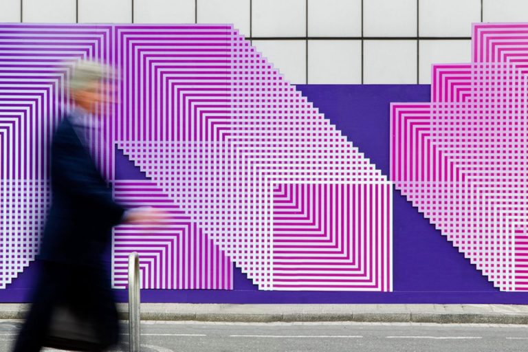 Pessoa fora de foco, andando por uma parede com um design diferenciado, representando o place branding