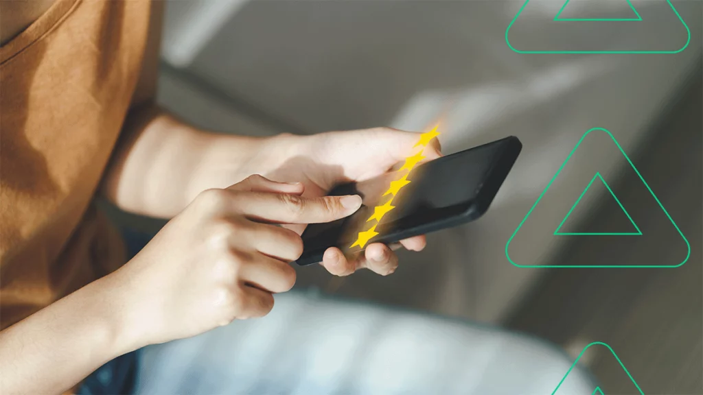 Close-up de uma pessoa segurando um celular e pressionando a tela, enquanto 5 estrelas flutuam na frente do aparelho