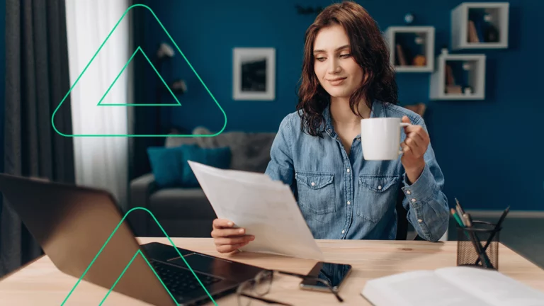 Mulher segurando uma caneca na mão enquanto avalia alguns boletos bancários em sua outra mão