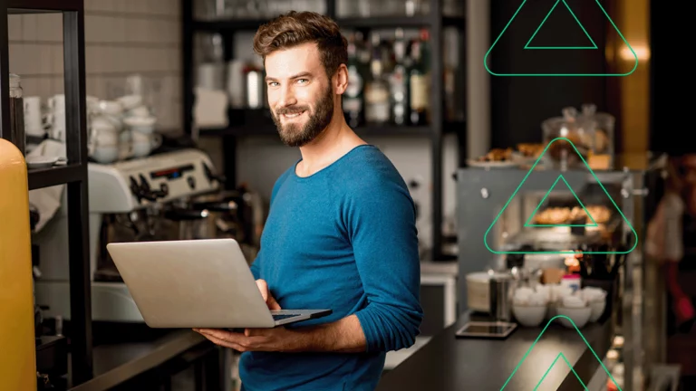 Empreendedor com seu computador na mão, sorrindo para a câmera, contente em ter ganhado um ingresso para o Vtex Day 2019