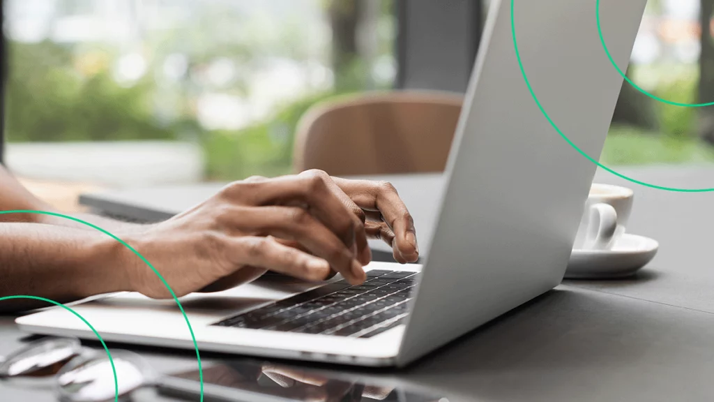 Close-up de mãos digitando em um notebook, pesquisando sobre o aniversário da Americanas.com