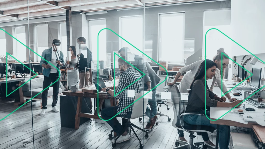 Foto panorâmica de um escritório, onde diversas pessoas trabalham e conversam em suas estações, se preparando para a Black Friday