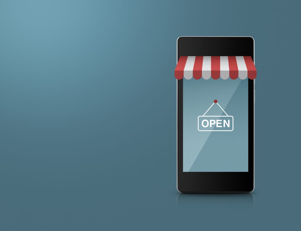 Em um fundo cinza, há um telefone celular enfeitado com uma fachada de loja, com uma placa de "open" na tela