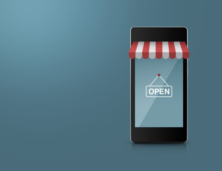 Em um fundo cinza, há um telefone celular enfeitado com uma fachada de loja, com uma placa de "open" na tela