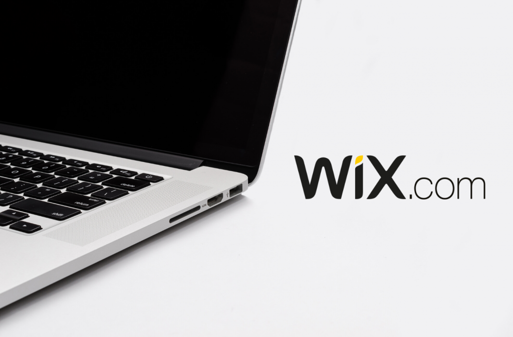 Foto de uma parte de um laptop, com o logotipo Wix.com em destaque ao lado