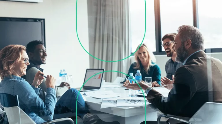 Várias pessoas conversando e sorrindo numa sala de reuniões de uma empresa