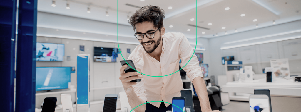 Empreendedor na sua loja de eletrônicos conferindo o Facebook em seu celular