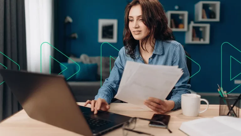 Empreendedora segurando relatórios e contas na mão enquanto pesquisa sobre conta digital MEI no notebook