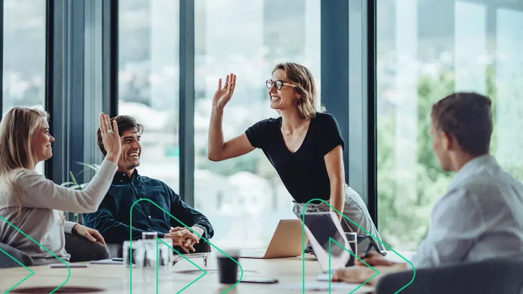 Duas mulheres se preparando para tocar as mãos num gesto de comemoração durante uma reunião de negócios