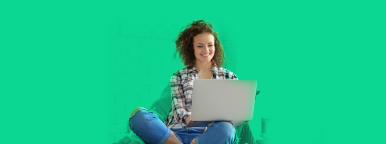 Mulher sentada com um laptop no colo, sorrindo ao entender como funciona o MEI