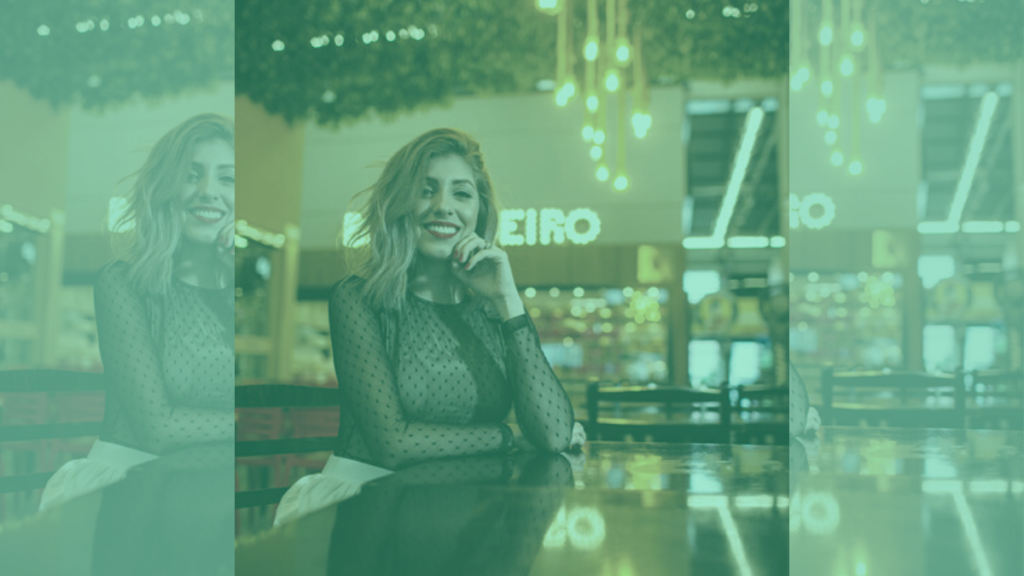 Dona de negócio sorrindo para a câmera apoiada no balcão da sua loja