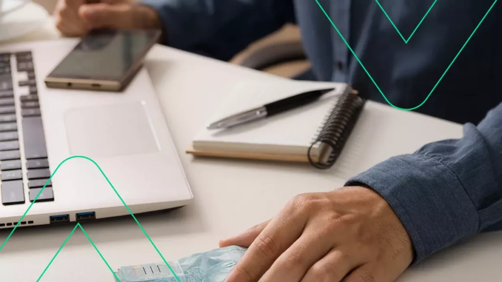 Empreendedor fazendo o cálculo do pró labore, com o computador, papel e caneta