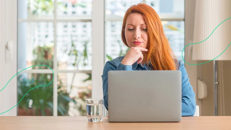 Empreendedora com expressão de curiosidade lendo no computador sobre o CFOP 5102