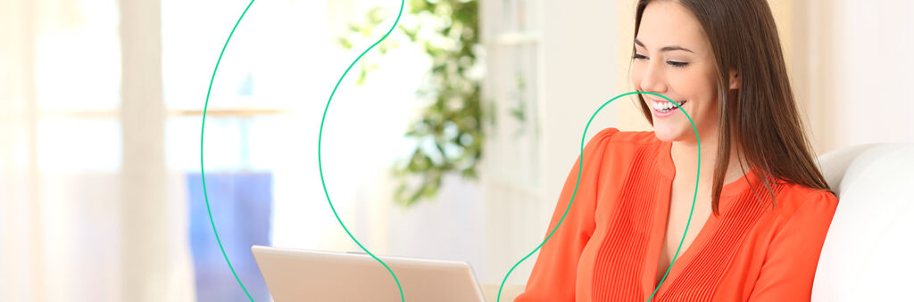Mulher sorrindo enquanto olha para o computador, ao descobrir o que é patrimônio