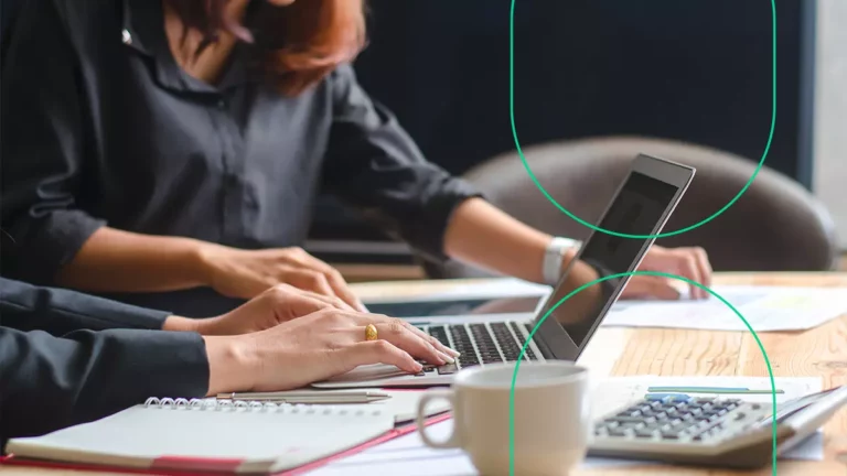 Mãos de mulheres em frente a um computador, com uma delas digitando