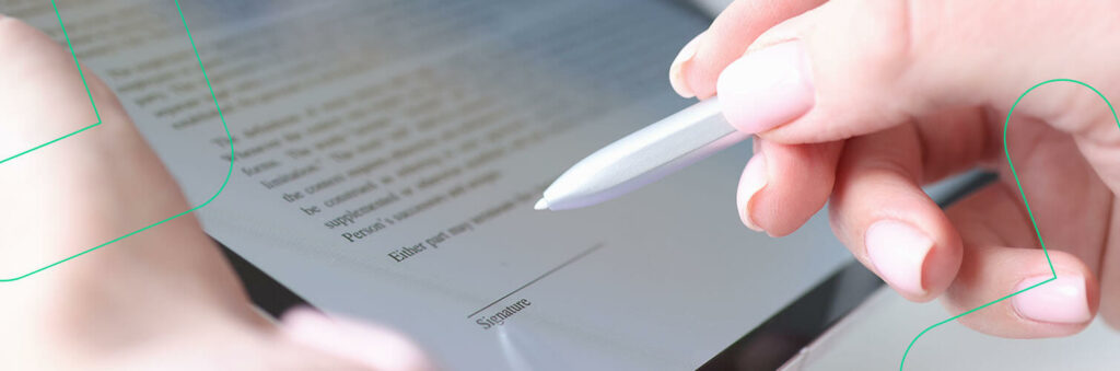 Close-up de uma mão segurando uma caneta sobre um documento, prestes a assiná-lo