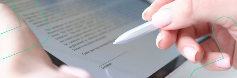 Close-up de uma mão segurando uma caneta sobre um documento, prestes a assiná-lo